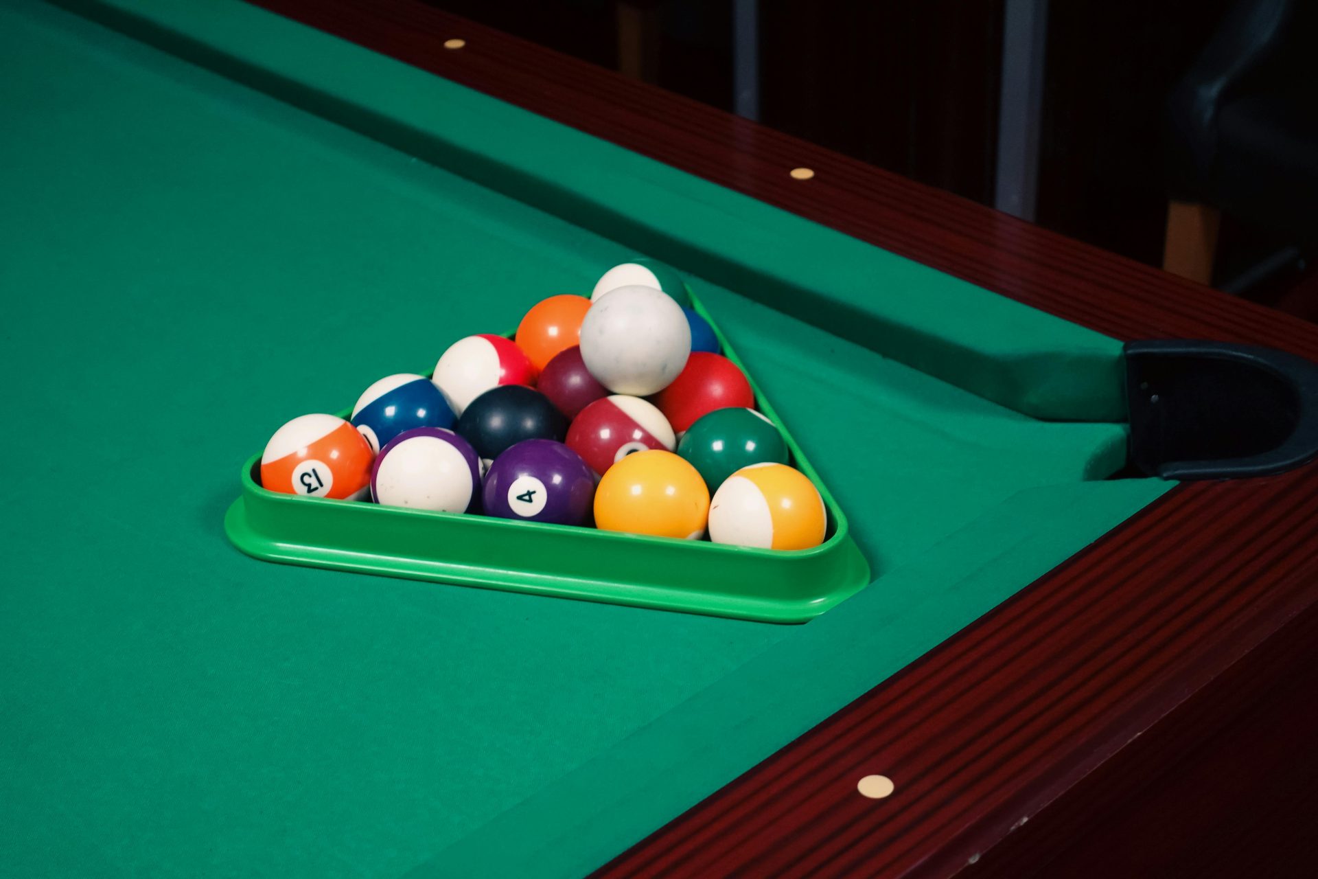 Un conjunto de coloridas bolas de billar dispuestas en forma de triángulo sobre una mesa de billar verde, listas para una partida.